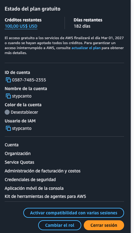 Menú de cuenta desplegado: "Estado del plan gratuito" con Créditos restantes 100,00 US$ USD y Días restantes 182 días, luego ID de cuenta, Nombre de la cuenta stypcanto, Color de la cuenta, y el campo "Usuario de IAM: stypcanto" — seguido de los enlaces Cuenta, Organización, Service Quotas, Administración de facturación y costos, Credenciales de seguridad, y los botones Cambiar el rol / Cerrar sesión